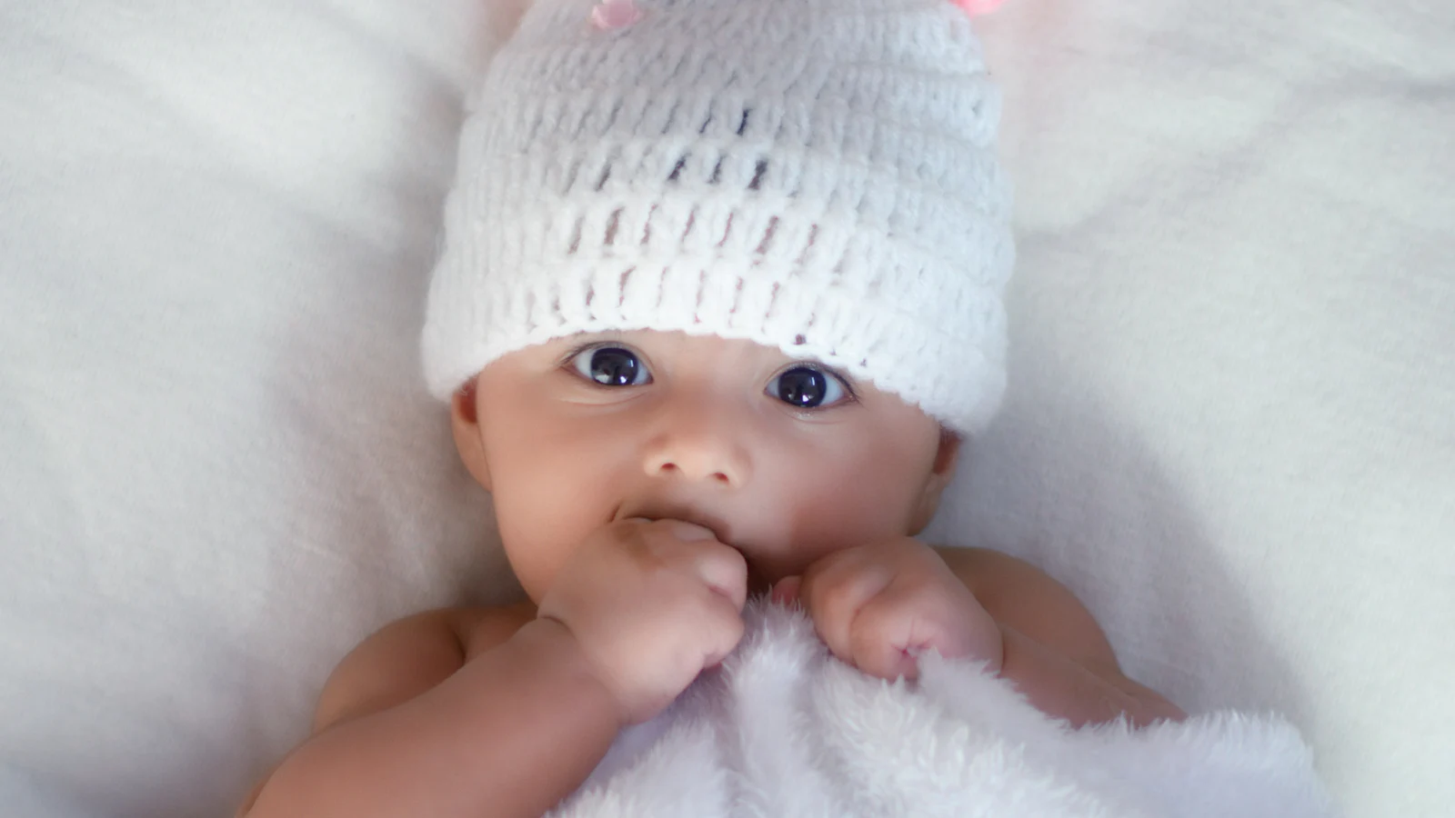 Baby mit weicher weißer Strickmütze.
