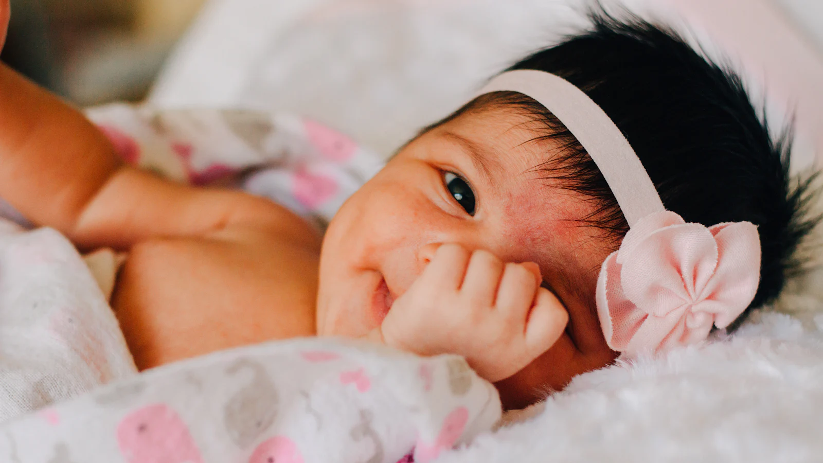 Baby mit weichem, weißem Blumen-Stirnband.