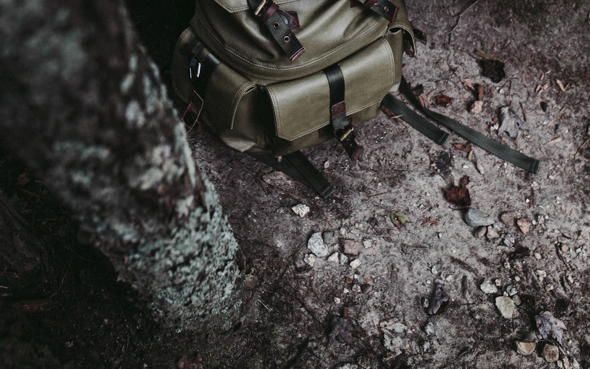 Canvas-Rucksack mit Lederriemen vor Waldboden.