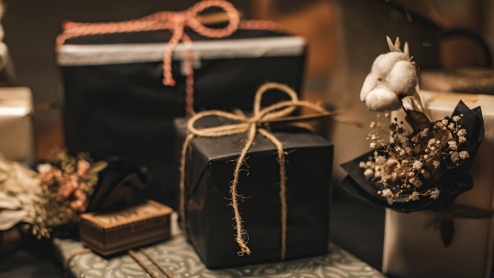 Verpacktes Geschenk auf gemustertem Stoff mit floralem Muster.