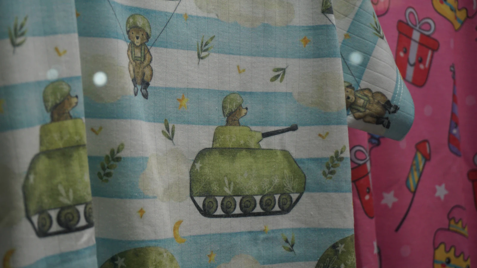 Bunter Kinderstoff mit Bären- und Panzer-Motiv, im Wind wehend.