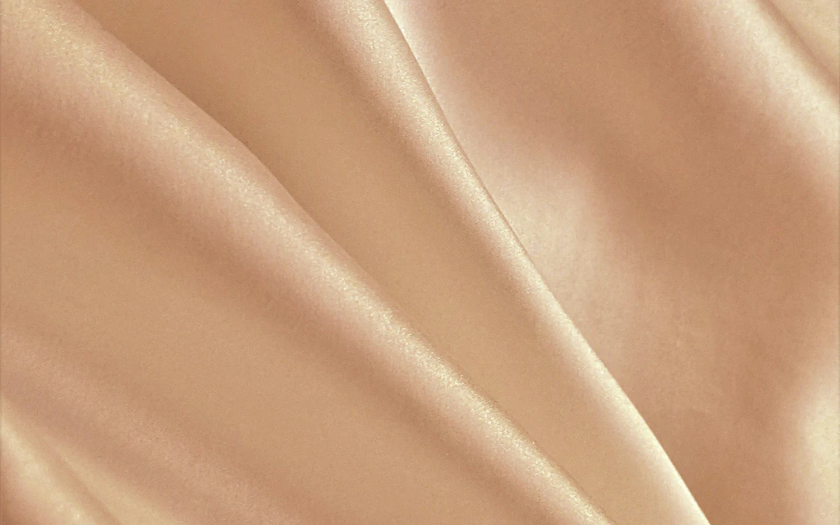 Beige, seidig glänzender Rayon-Stoff in weichen Falten.