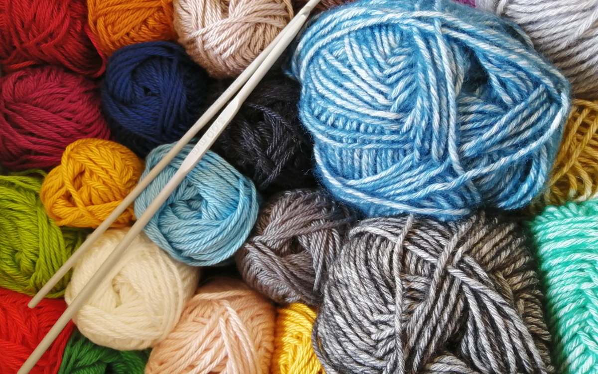 Bunte Wollknäuel mit einer langen Nadel in der Mitte.