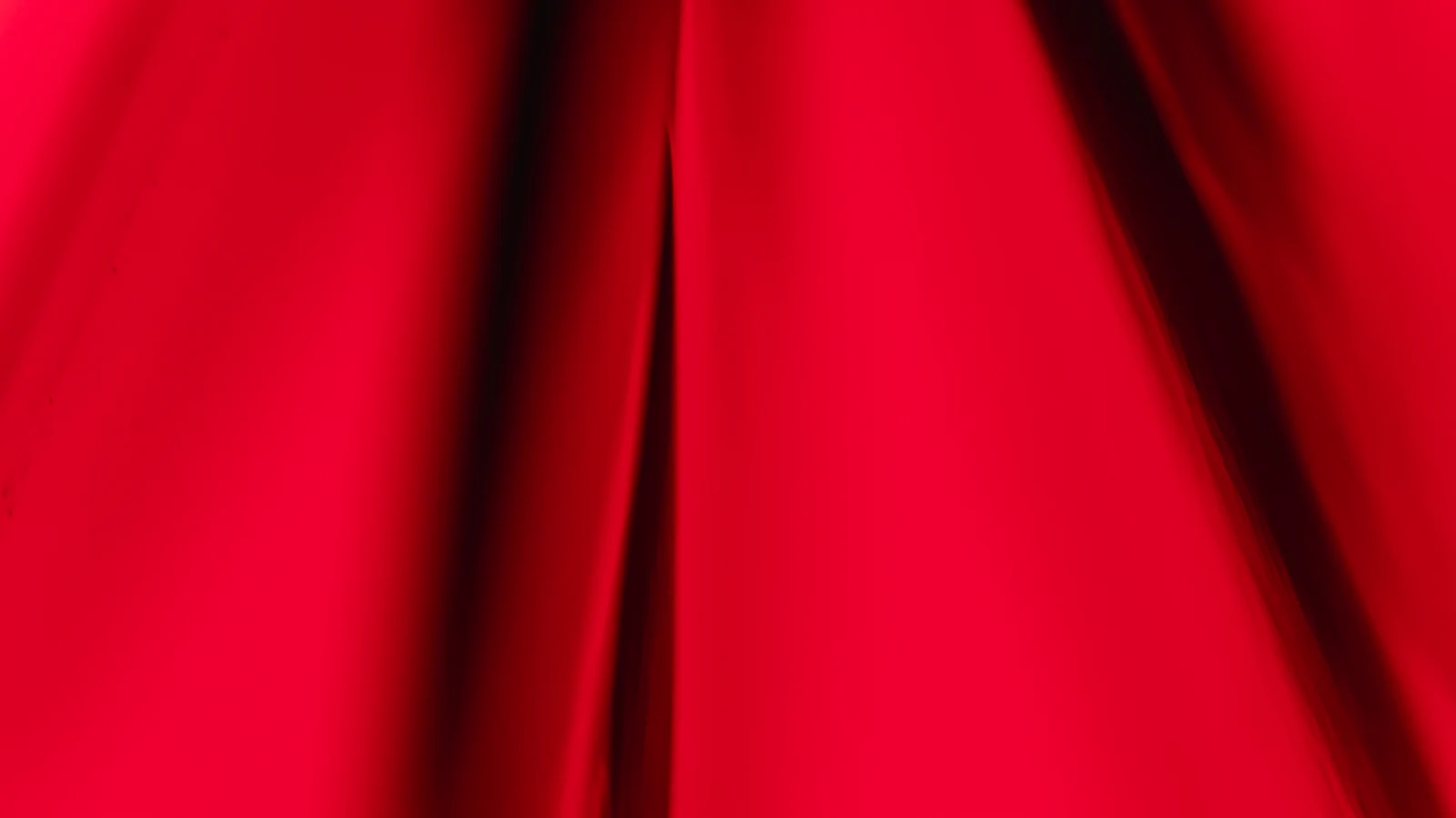 Roter Samtstoff in weichen Falten mit sichtbarem Lichtspiel.